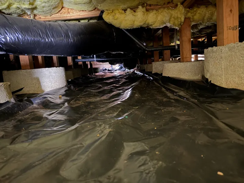 New black barrier fit around concrete piers in a crawl space